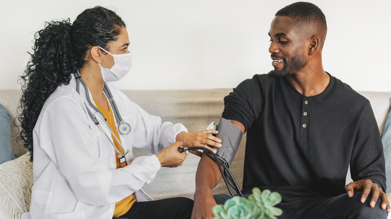 doctor taking young man's blood pressure