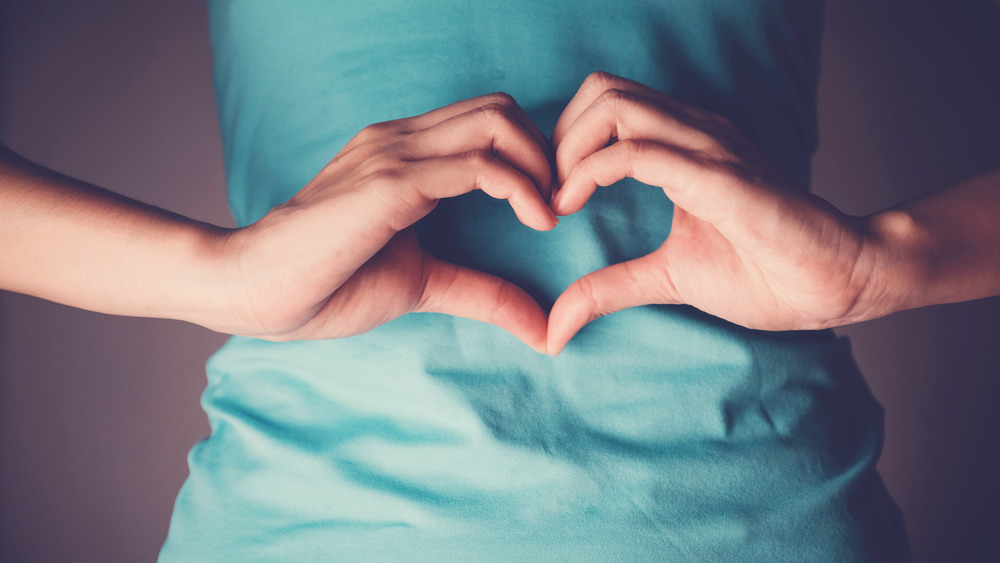 woman making heart shape on stomach