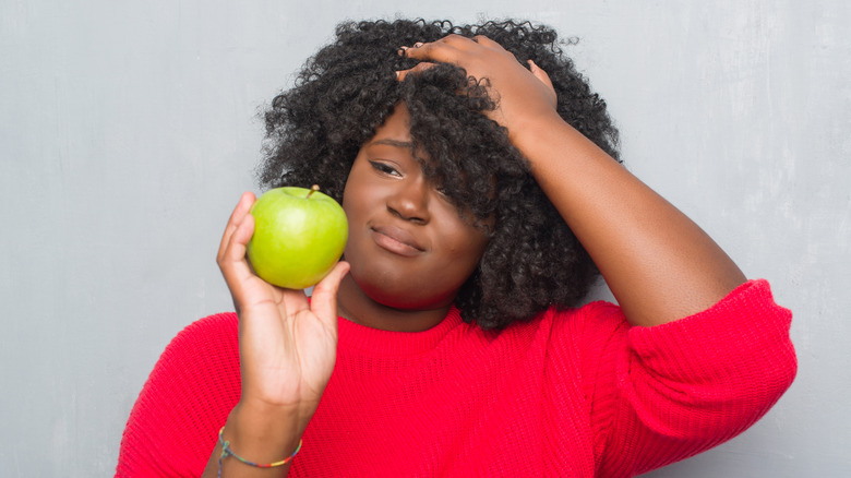 woman looking at green apple