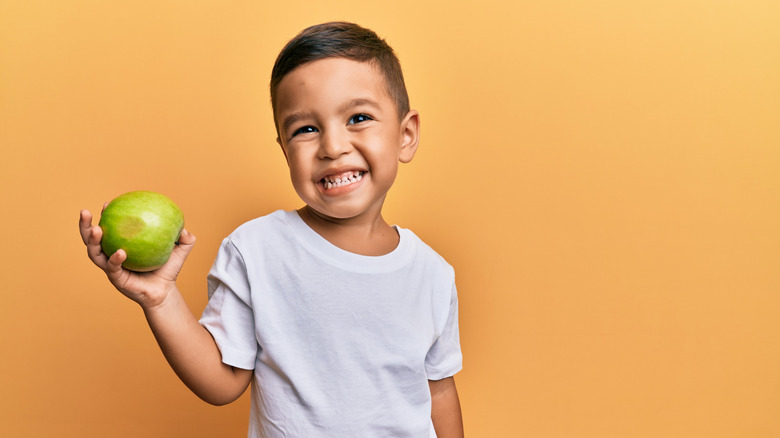 smiling toddler holding apple 