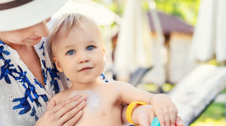 mom puts sunscreen on toddler