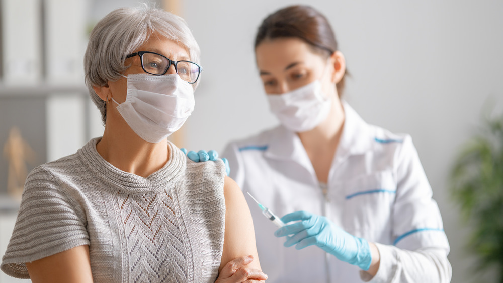 doctor giving a senior woman a vaccine