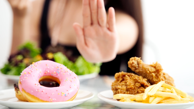 woman pushing away sweets and junk food