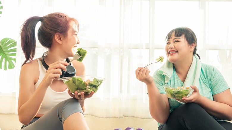 two women eating salad after exercise