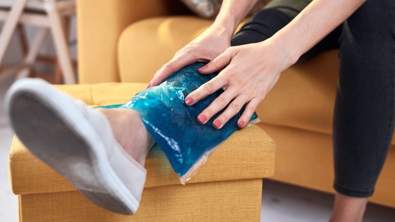 woman applies ice pack to leg