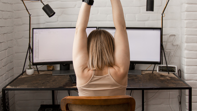 woman on computer stretching 