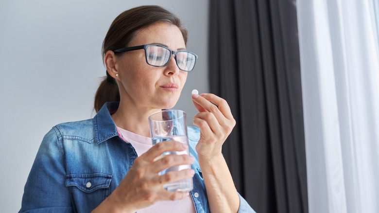 A woman taking medication for a headache