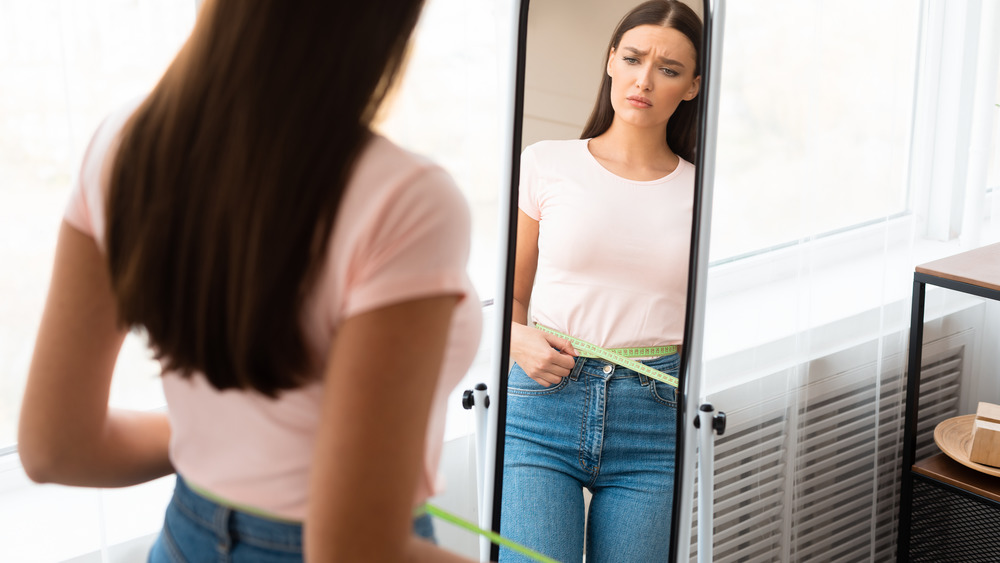 woman looking at weight in mirror