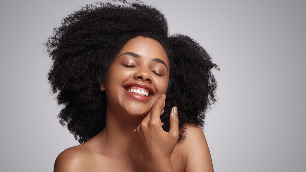 woman smiling and touching face