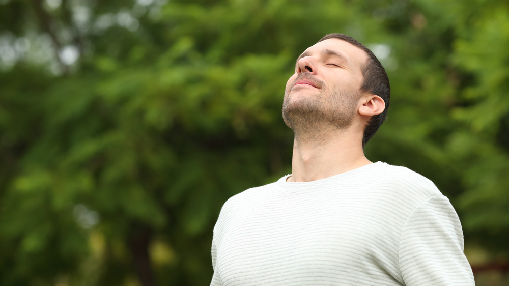 man outside breathing and looking happy