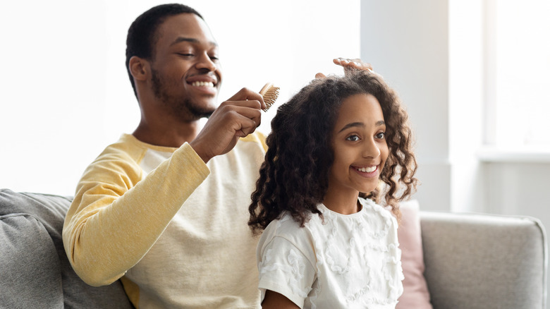 a dad brushing his daughter's hair