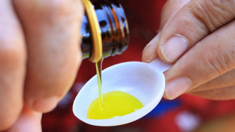 liquid medicine being poured into spoon