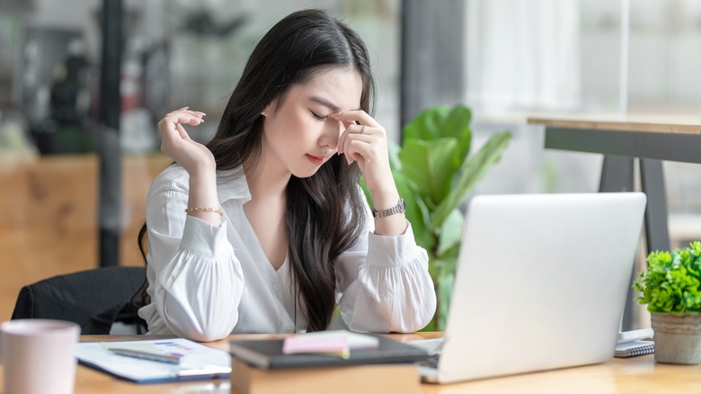 woman feeling migraine at desk