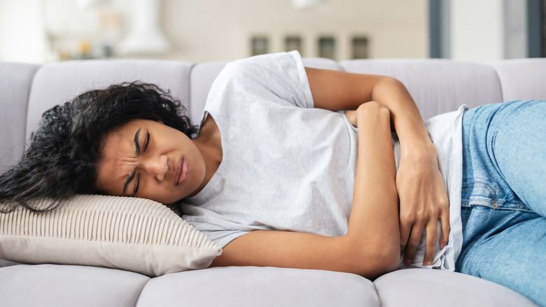 woman lying on couch with period pain