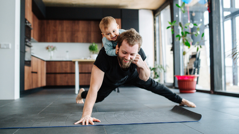 young father exercising with a child on his back 