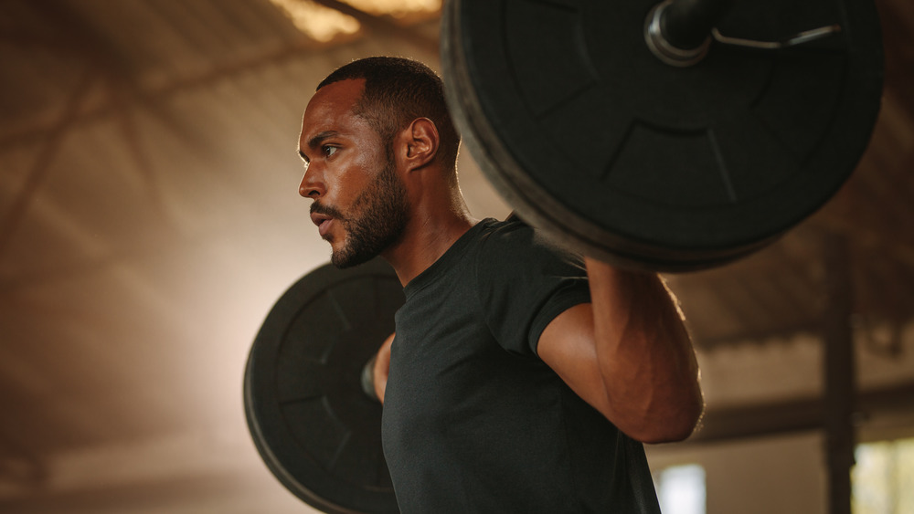 man using barbell to squat