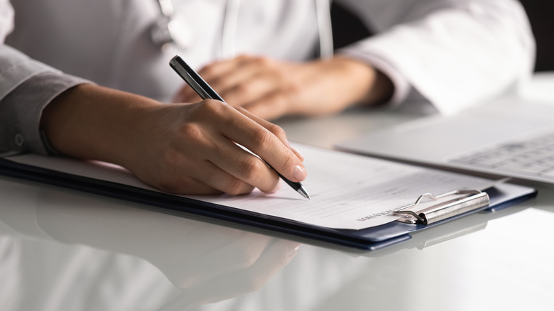 Close up of a doctor writing on a patient's chart