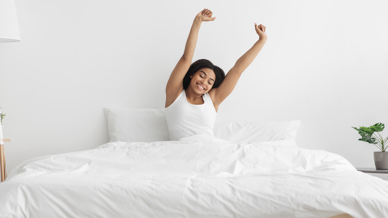 Smiling woman stretching in bed