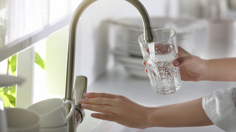 woman's hand drawing tap water in a kitchen