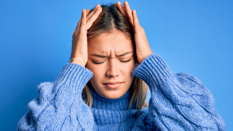 woman in blue holding head