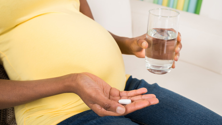 pregnant womans holding glass and acetaminophen