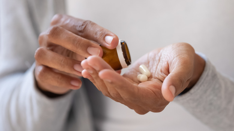 woman putting pills in hand