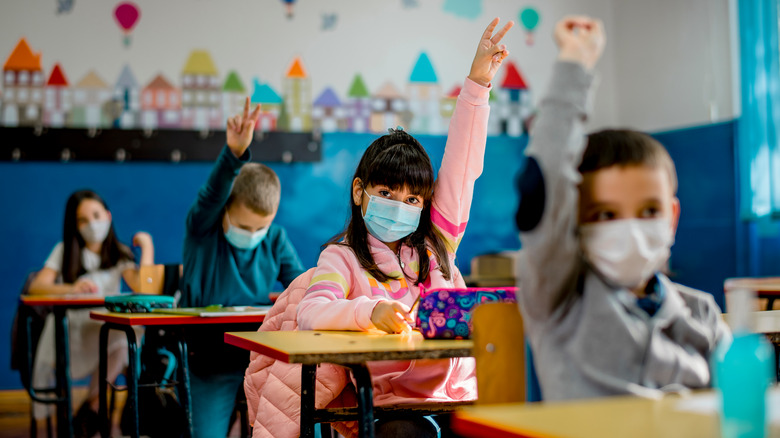 Kids raise hands in classroom