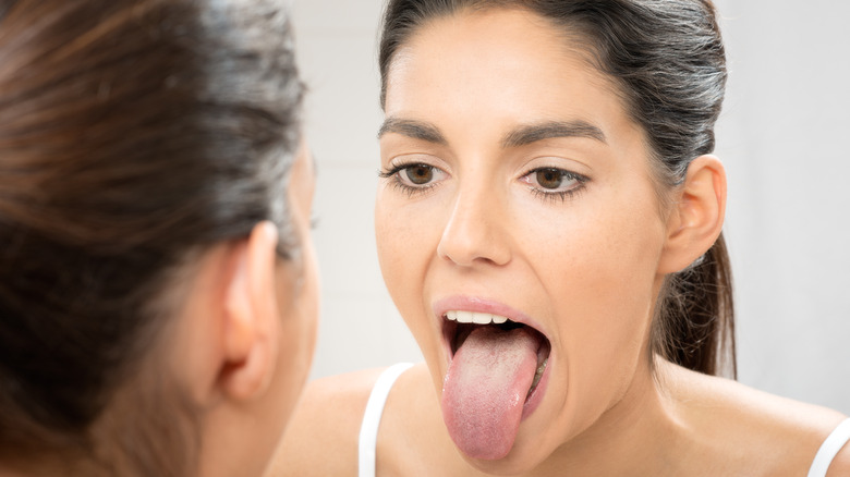 Woman checking her tongue in mirror