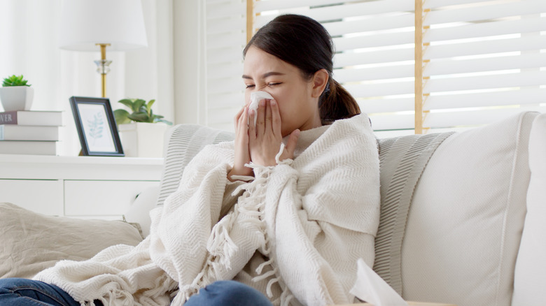 Young woman sneezing on couch