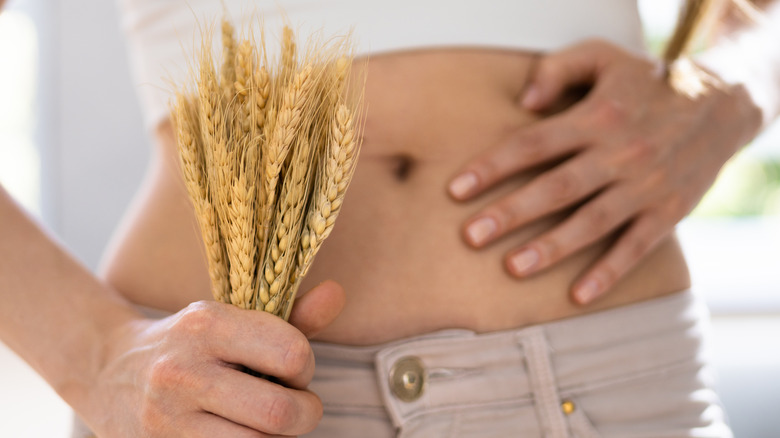Woman holding wheat near belly