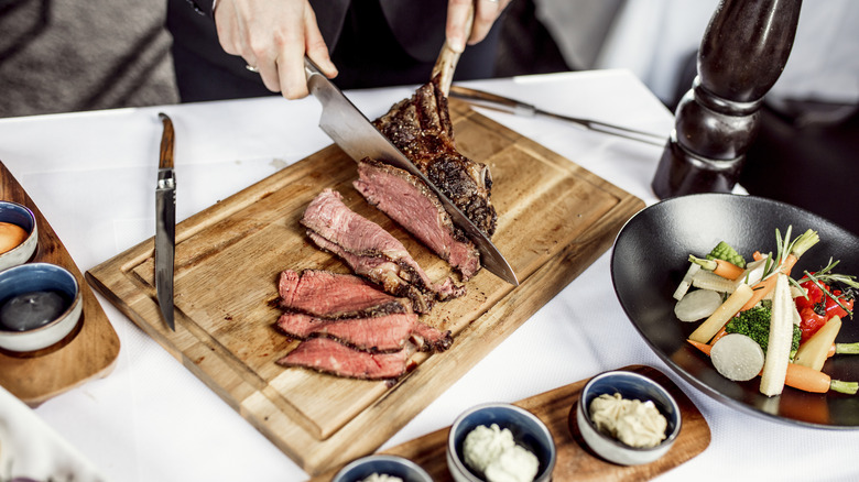 person cutting steak at a table