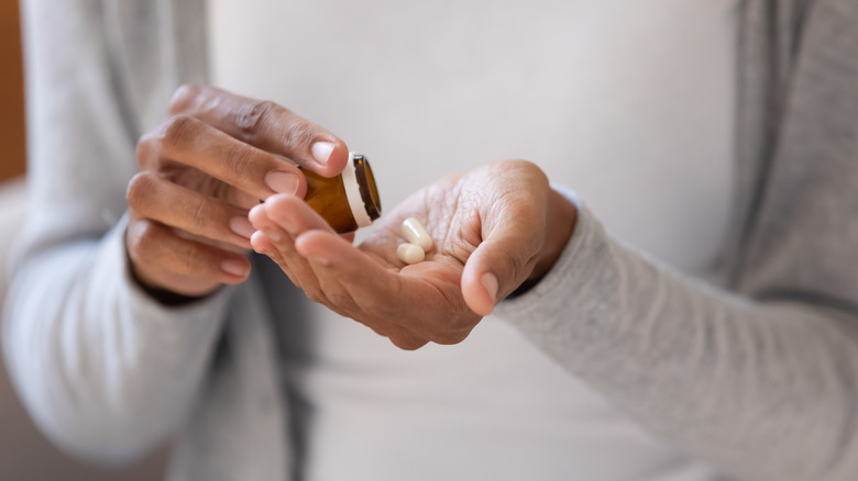 Hands pouring medication from bottle