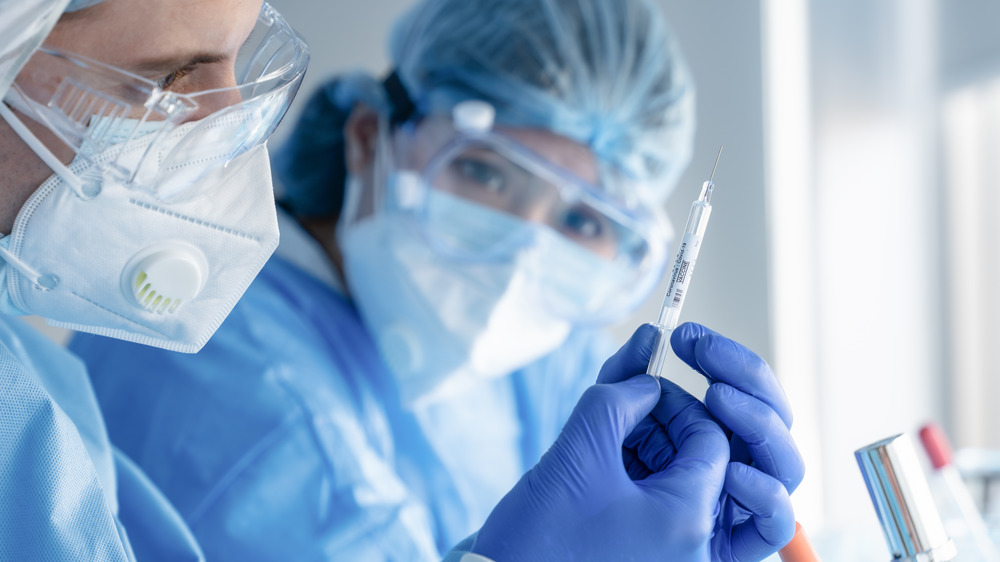 stock photo of two medical workers and a vaccine syringe