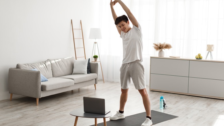 man doing side stretches in his living room