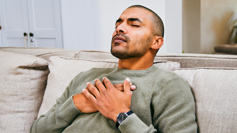 man sitting on couch having trouble breathing