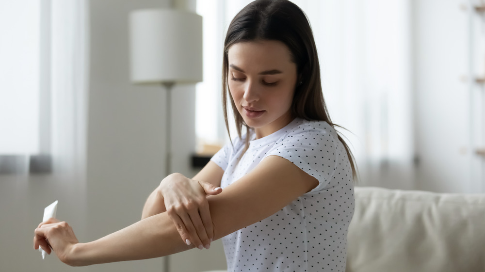 Woman putting lotion on arms