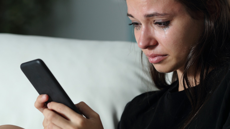 Girl crying while looking at phone