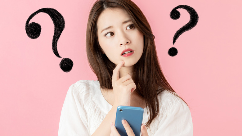 Woman holding her phone looking confused