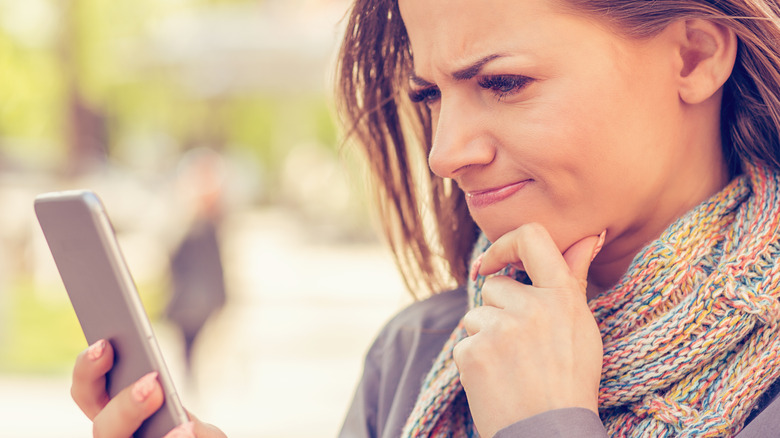 Woman checking phone with skeptical look
