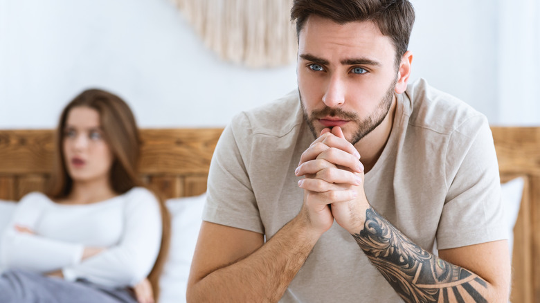 young couple on bed with concerned look on their faces