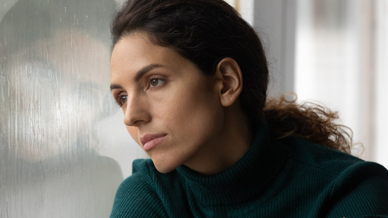 young female staring out a dusty window