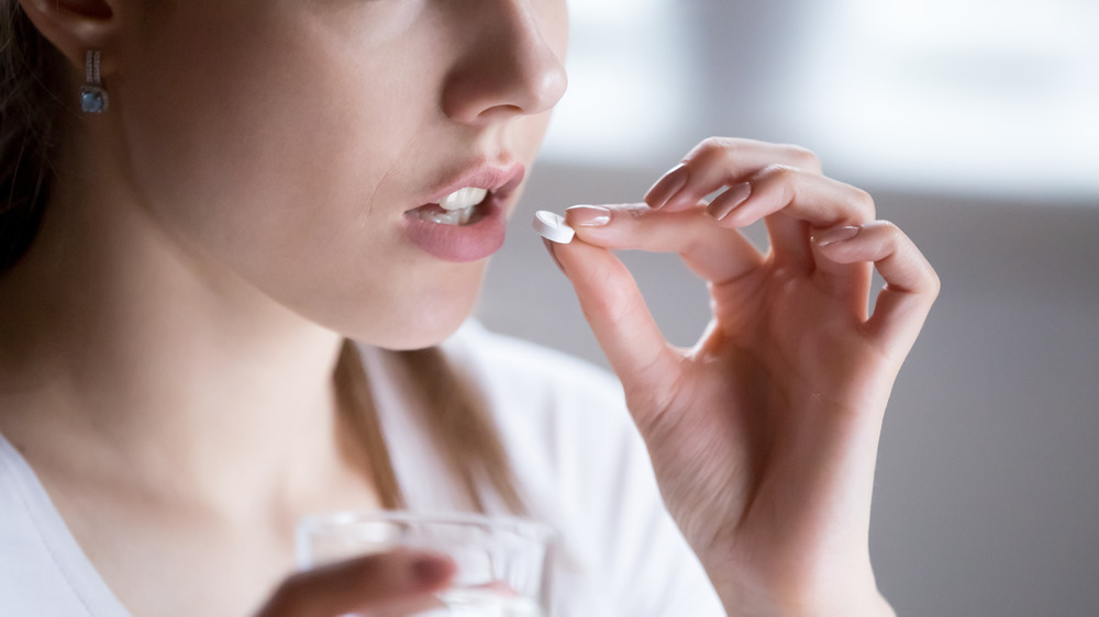 Woman taking pill with water