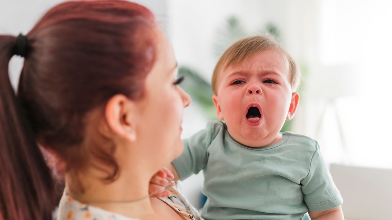 A woman holds a coughing baby