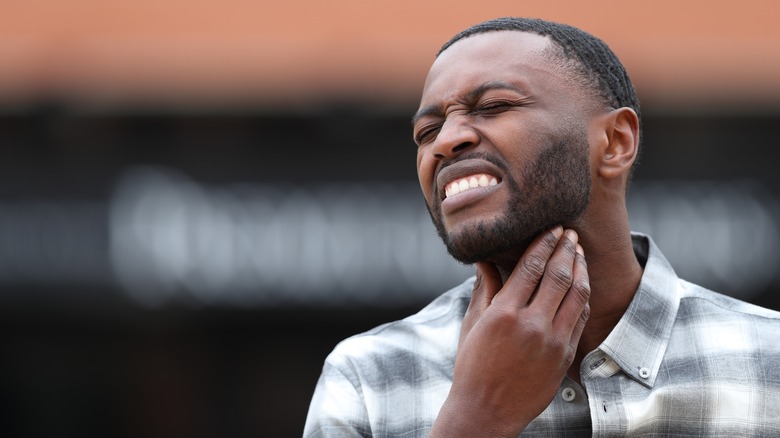 Man holding sore throat