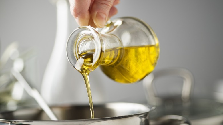 close-up hand pouring olive oil