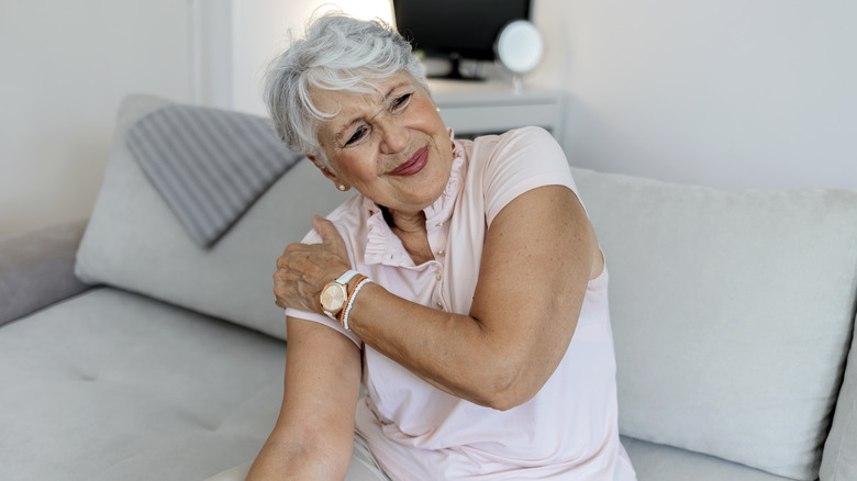 Wincing older woman holding shoulder