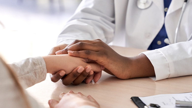 Close up of doctor holding patient's hand