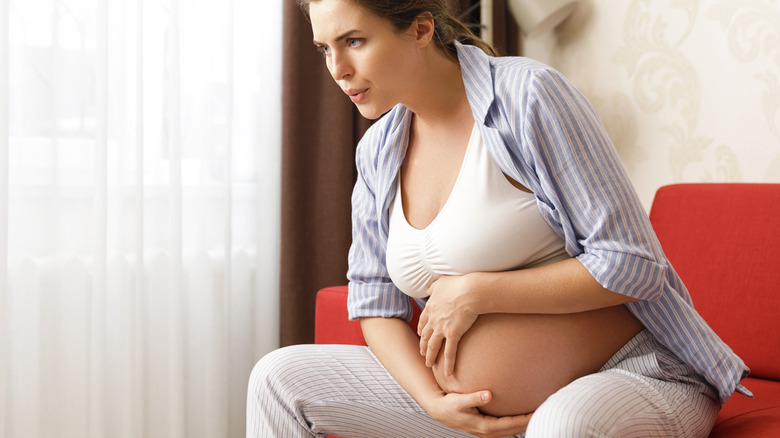 pregnant woman holding belly having hard time breathing 