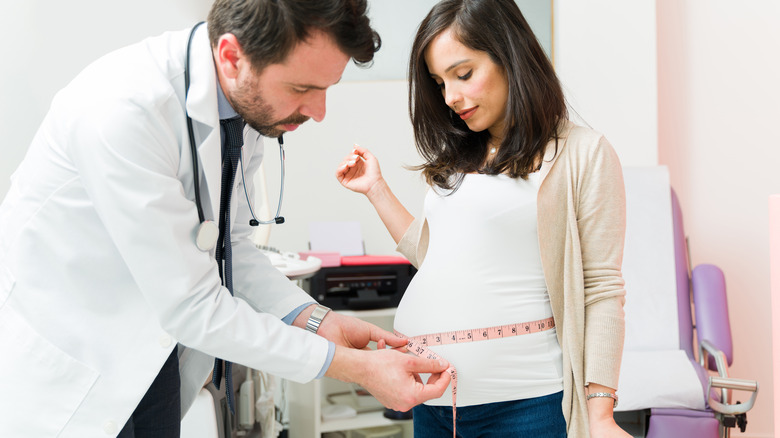 doctor measuring belly of pregnant woman 