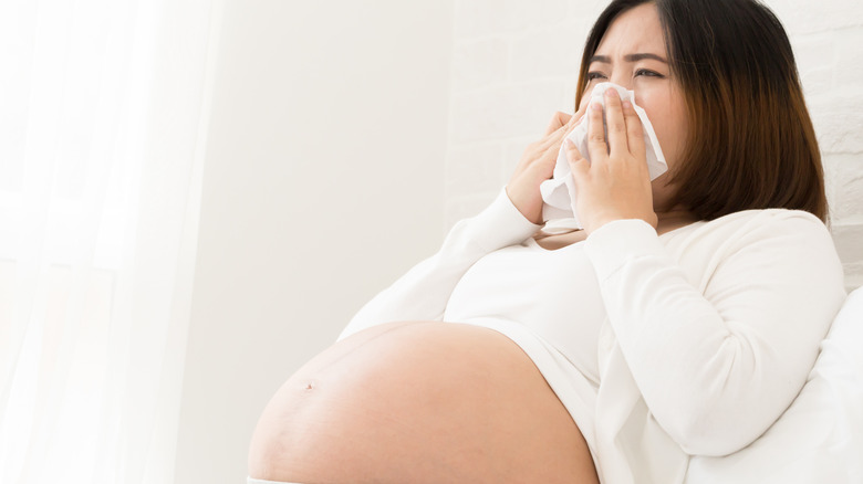 pregnant woman blowing nose